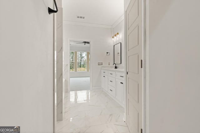 corridor featuring marble finish floor, crown molding, visible vents, a sink, and baseboards