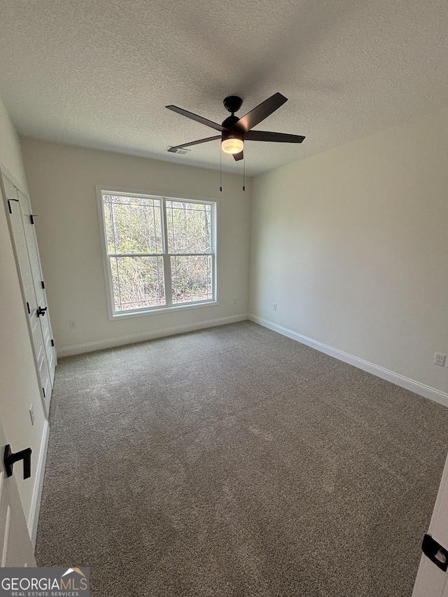 unfurnished bedroom featuring ceiling fan, a textured ceiling, baseboards, and carpet