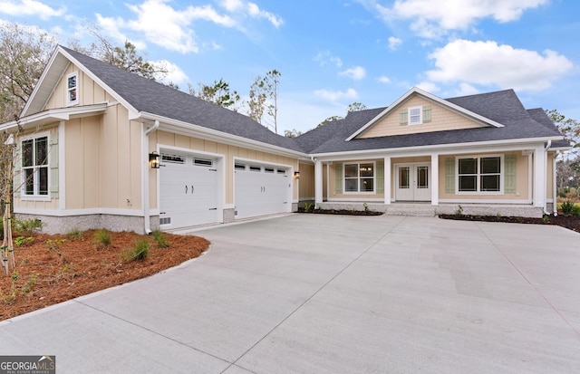 view of front of property with a garage, a shingled roof, concrete driveway, french doors, and board and batten siding