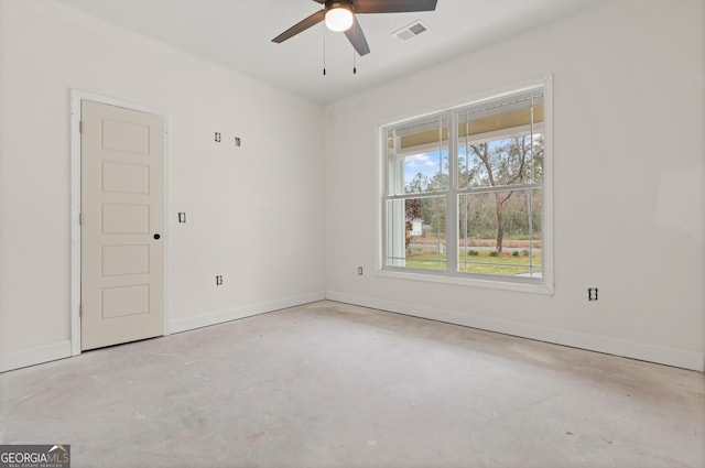 spare room featuring baseboards, concrete floors, visible vents, and a ceiling fan