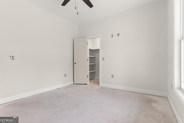 empty room featuring ceiling fan, unfinished concrete flooring, and baseboards