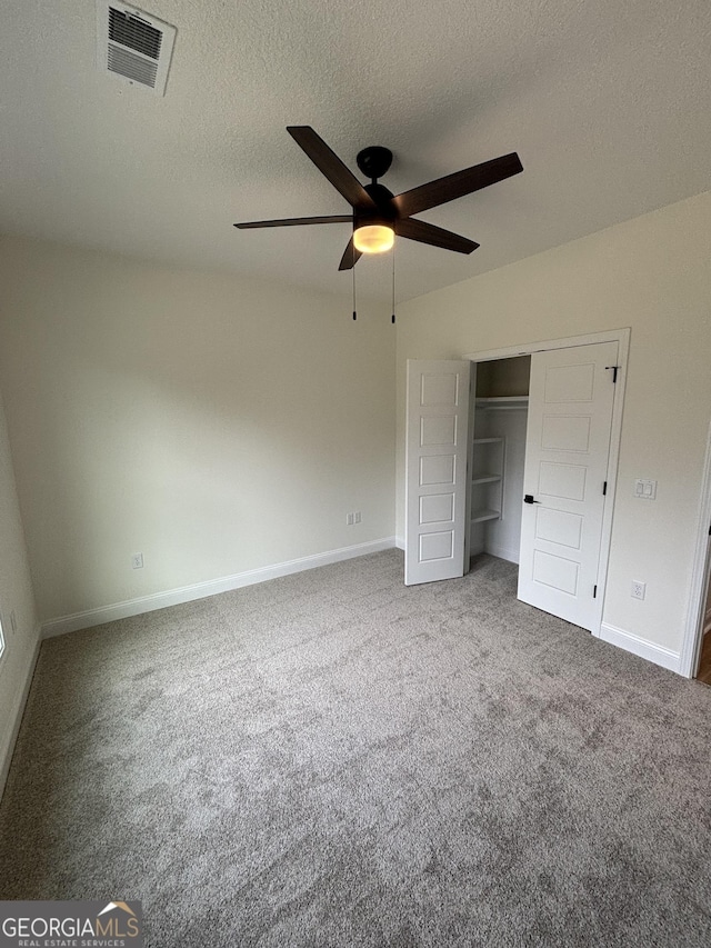 unfurnished bedroom featuring visible vents, baseboards, carpet floors, a closet, and a textured ceiling