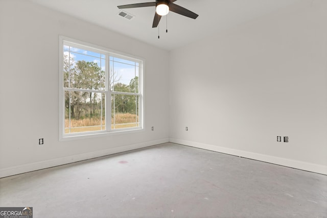 spare room with a ceiling fan, visible vents, unfinished concrete flooring, and baseboards