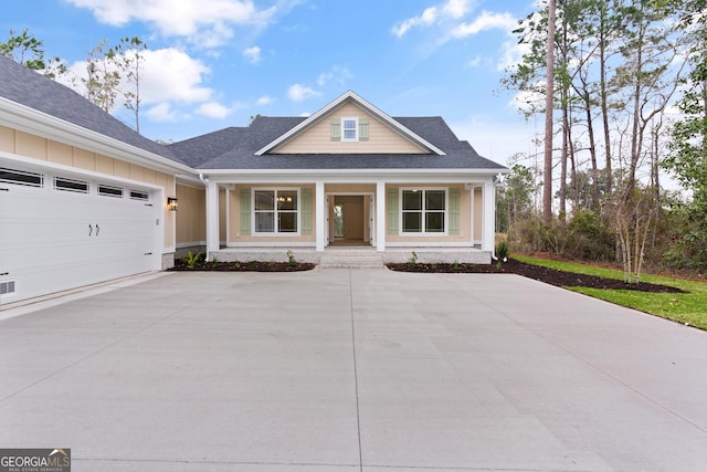 view of front facade featuring a porch, an attached garage, a shingled roof, concrete driveway, and board and batten siding