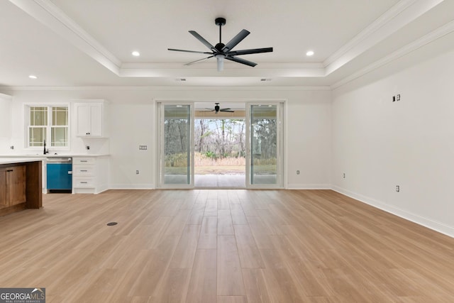 unfurnished living room with recessed lighting, baseboards, ornamental molding, light wood finished floors, and a raised ceiling