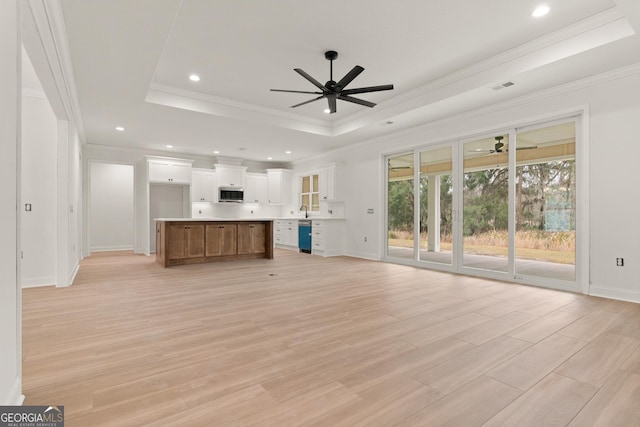 unfurnished living room featuring light wood-style floors, a raised ceiling, and a ceiling fan