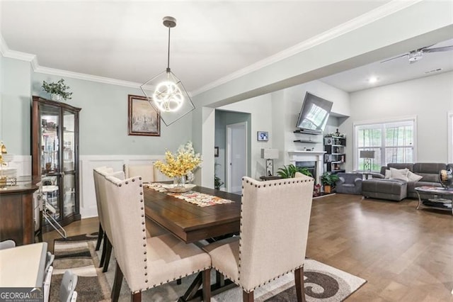 dining area featuring wood-type flooring, ceiling fan, and crown molding