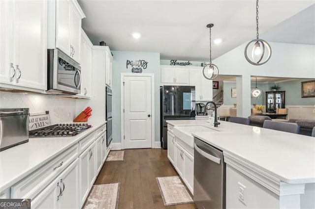 kitchen with tasteful backsplash, stainless steel appliances, a kitchen island with sink, white cabinetry, and hanging light fixtures