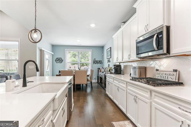 kitchen with white cabinets, decorative light fixtures, and stainless steel appliances