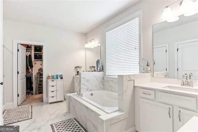 bathroom featuring tiled bath, a wealth of natural light, and vanity