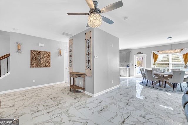 unfurnished living room featuring ceiling fan with notable chandelier