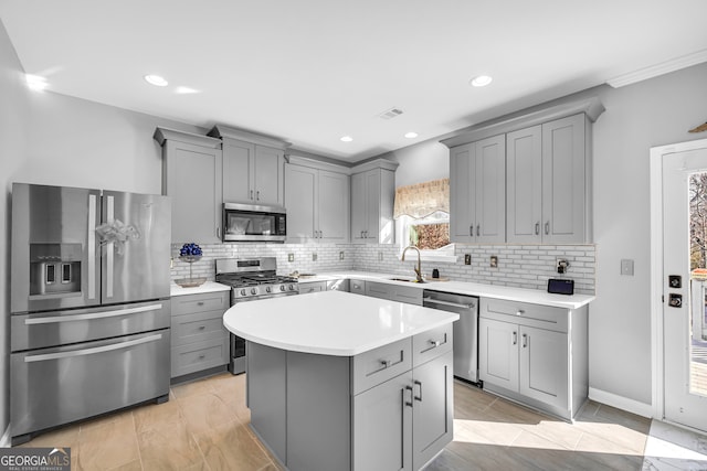 kitchen featuring tasteful backsplash, gray cabinetry, stainless steel appliances, and a kitchen island