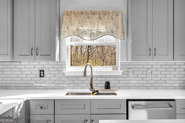 kitchen with decorative backsplash, sink, dishwasher, and gray cabinetry