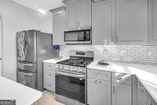 kitchen featuring gray cabinetry, stainless steel appliances, and decorative backsplash