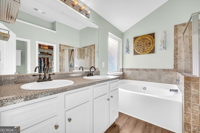 bathroom featuring hardwood / wood-style floors, vaulted ceiling, vanity, and plus walk in shower