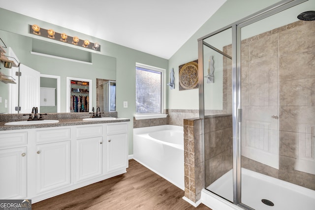 bathroom with lofted ceiling, vanity, wood-type flooring, and plus walk in shower