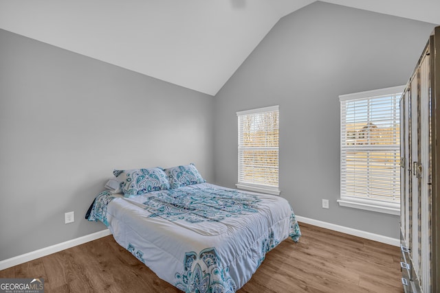 bedroom with high vaulted ceiling, multiple windows, and light hardwood / wood-style flooring