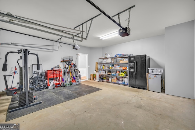 garage featuring fridge, a garage door opener, and black fridge with ice dispenser