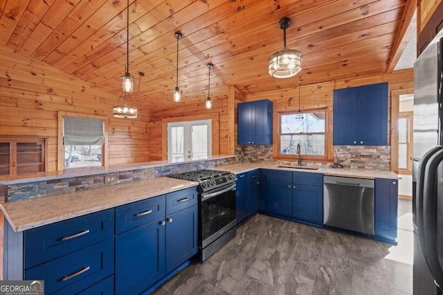 kitchen with pendant lighting, wood walls, blue cabinets, sink, and appliances with stainless steel finishes