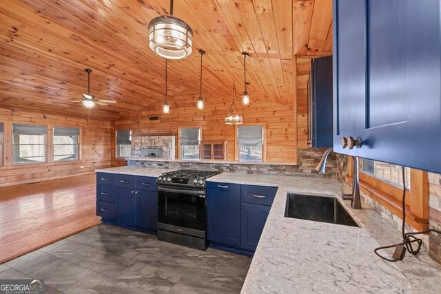 kitchen featuring pendant lighting, sink, wooden walls, and stainless steel range oven