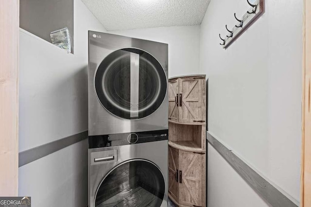 clothes washing area with a textured ceiling and stacked washer and dryer