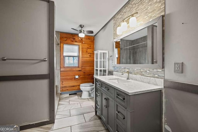 bathroom featuring backsplash, vanity, ceiling fan, toilet, and wood walls