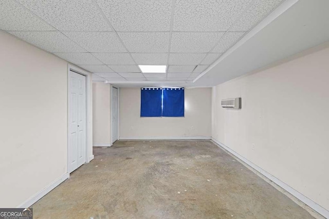 basement featuring a wall mounted AC and a drop ceiling