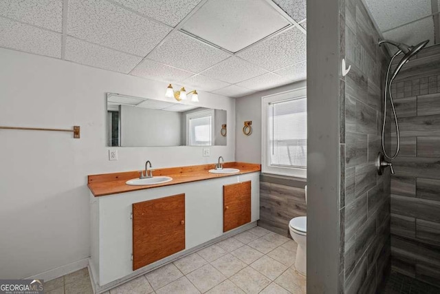 bathroom featuring vanity, toilet, a shower, and a drop ceiling