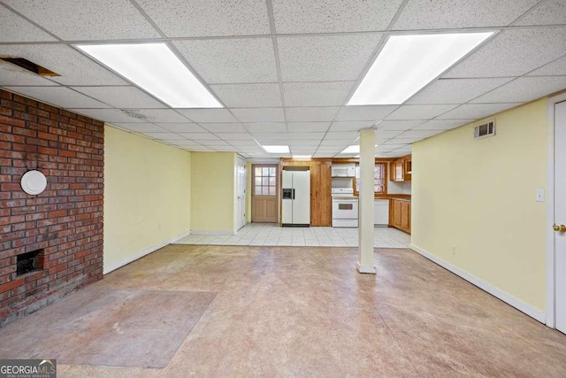 basement with a drop ceiling and white refrigerator with ice dispenser