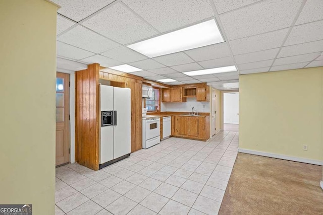 kitchen with white appliances, a drop ceiling, and sink