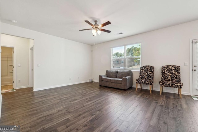 living area featuring ceiling fan and dark wood-type flooring