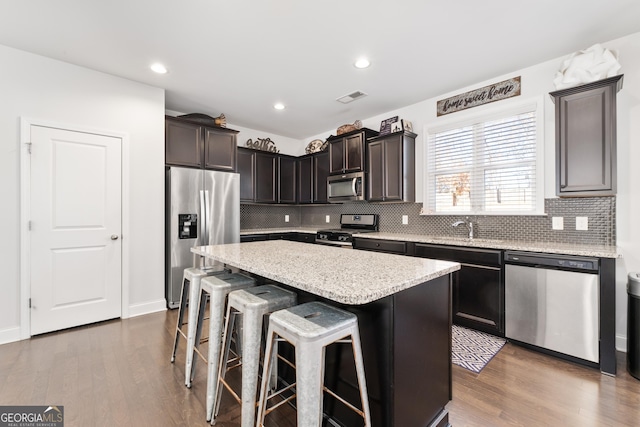 kitchen featuring light stone countertops, appliances with stainless steel finishes, dark hardwood / wood-style floors, and a kitchen island