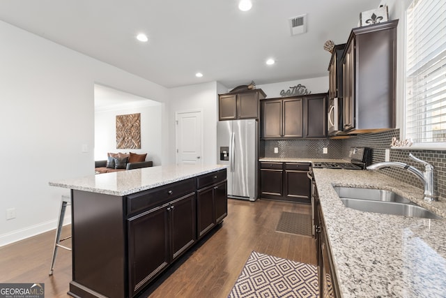 kitchen with dark wood-type flooring, sink, a kitchen island, and stainless steel appliances