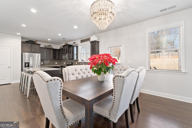 dining area with a healthy amount of sunlight, dark wood-type flooring, and a notable chandelier