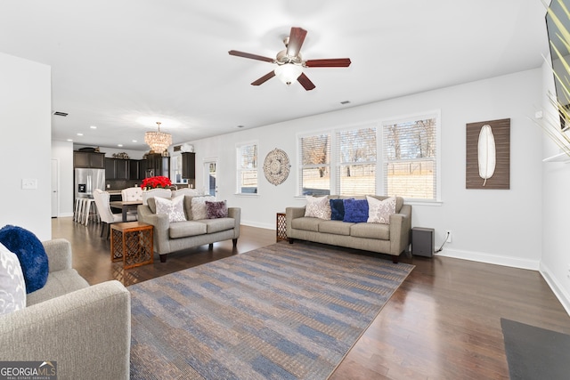 living room with ceiling fan with notable chandelier and dark wood-type flooring