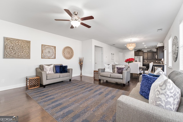 living room featuring ceiling fan with notable chandelier and dark hardwood / wood-style flooring