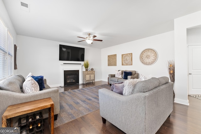 living room featuring ceiling fan, plenty of natural light, and dark wood-type flooring