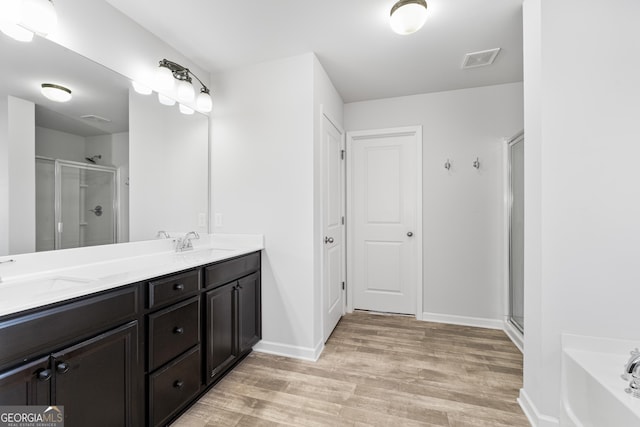 bathroom featuring vanity, wood-type flooring, and plus walk in shower