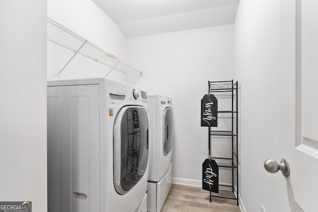 washroom with washer and clothes dryer and light hardwood / wood-style flooring