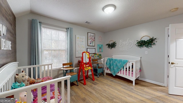 bedroom featuring a textured ceiling, vaulted ceiling, and light wood-type flooring