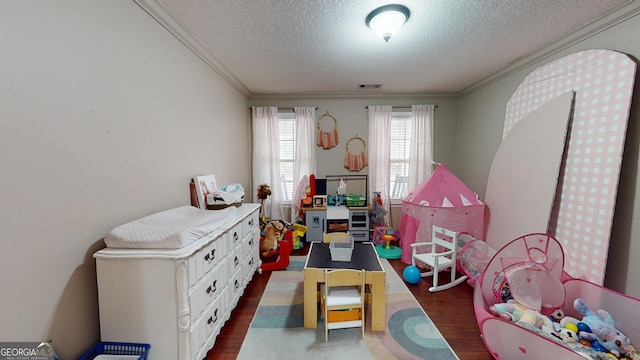 playroom featuring a textured ceiling, crown molding, and dark wood-type flooring