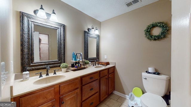 bathroom with tile patterned flooring, vanity, toilet, and a textured ceiling