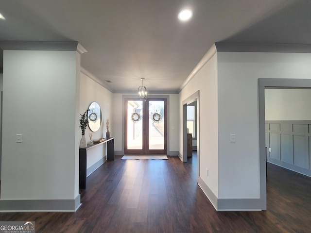 entryway with a notable chandelier, french doors, crown molding, and dark wood-type flooring