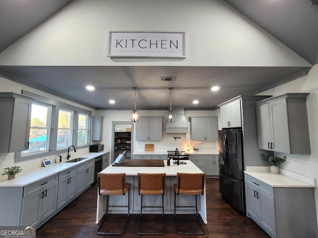 kitchen featuring black fridge, dark hardwood / wood-style flooring, a kitchen bar, gray cabinets, and a kitchen island with sink