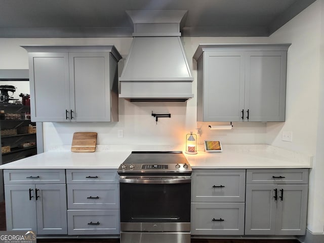 kitchen with gray cabinetry, premium range hood, and stainless steel range with electric cooktop