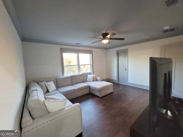 living room with crown molding, ceiling fan, and dark wood-type flooring