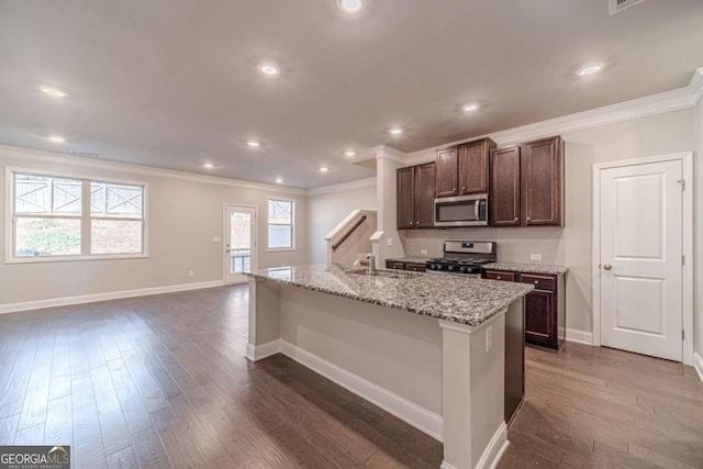 kitchen with plenty of natural light, light stone countertops, an island with sink, and appliances with stainless steel finishes