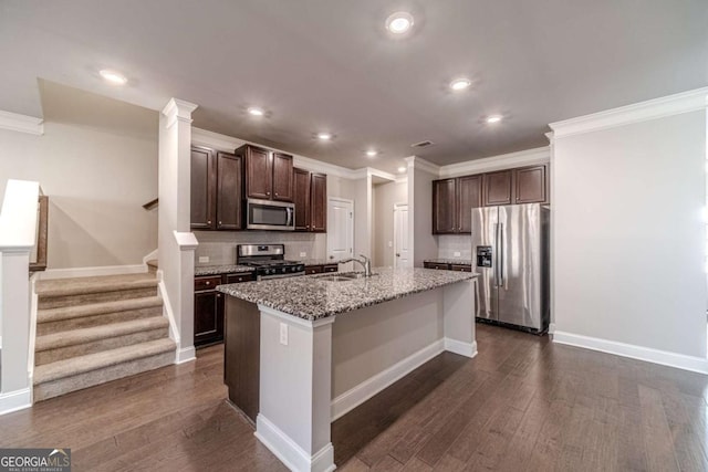 kitchen featuring appliances with stainless steel finishes, dark brown cabinetry, a kitchen island with sink, and sink