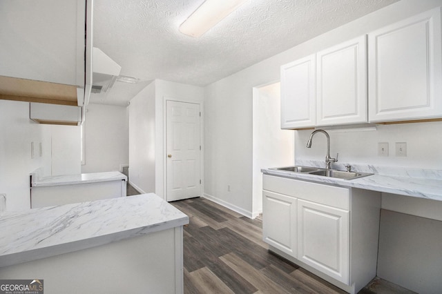 kitchen with dark hardwood / wood-style floors, white cabinetry, sink, and a textured ceiling