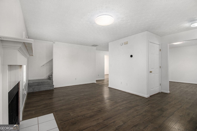 unfurnished living room featuring dark wood-type flooring and a textured ceiling